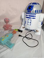 Photo of R2D2 popcorn popper with power cord, E.T. plush doll, and Rick and Morty space toy ray gun in packaging