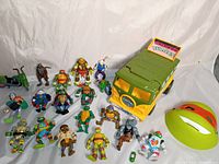 Photo showing 17 TMNT action figures arranged standing and lying with the Turtle Van and the Michelangelo mask.