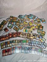 Wide layout view of over 300 Magic The Gathering cards sorted by colors and types, many in protective slide cases, showing the variety and condition of the cards.
