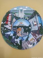 Photo of a round, 10-inch diameter ceramic plate with decorative, raised depictions of Quebec City landmarks segmented around the plate. Central scene shows 'QUEBEC' and a ferry on the water.