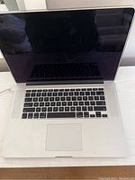 Front view of Apple MacBook Pro laptop open showing screen, keyboard and trackpad.