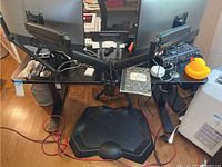 Front view of black electric standing desk with cluttered top and dual monitors