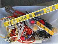 Top view of the lot showing yellow contractor level, bolt cutters, extension cords, WD-40, brush, power strips, and some cables.