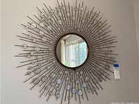 Full view of the circular wall mirror showing the metal rods and glass disc design in a burst pattern.