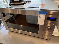 Front angled view of Panasonic stainless steel microwave showing control panel, digital display, door, and overall condition.