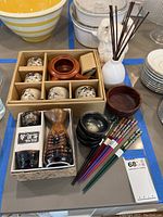 Full lot overview showing all items: ceramic sake bottle and cups, decorated small sake cups in cardboard holder, wooden bowl, black ceramic bowls, six pairs of chopsticks, and terracotta item