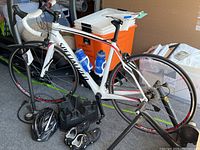 Side view of white Specialized road bike on trainer stand with two water bottles and phone mount