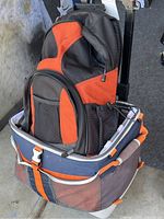 Photo of Tamrac black and orange photographer's backpack placed inside the insulated wheeled cooler bag