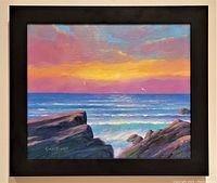 Full front image of the oil painting showing colorful seascape with rocks and sunrise sky in new black frame.
