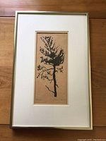 Full view of framed tree print showing off white mat and simple frame against wooden background.