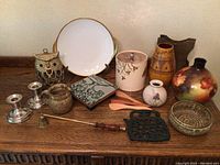 Photo of all items on table including various pottery, metal, and wooden decorative objects