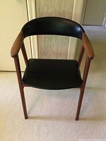 Front view of the retro wooden armchair showing black vinyl seat and backrest with wooden armrests and legs.