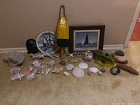 Front view of assorted sea-themed collectibles including shells, coral, fishing bobber, framed sailboat print, and ceramic fish figure.