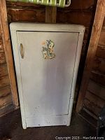 Front view of white vintage metal cabinet with Bambi decal on the door, showing wear and metal handle.