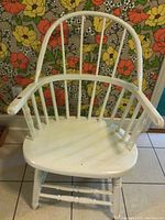 Front view of the white wooden armchair with spindle back and rounded armrests.
