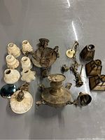 Photo showing numerous antique lighting parts including ceiling fixtures, various hanging chains, and multiple lamp shades in cream and brown tones.