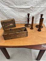 Photo of four wooden candle holders and one wooden box on a table.