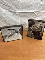 Two rectangular plaques showing black and white vintage military photos, one male soldier smoking pipe, one female soldier with weapon