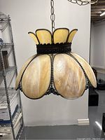 Photo of stained glass swag lamp with metal framing, yellowish stained glass petals, hanging chain and electrical cord.