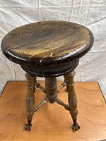 Front view of adjustable piano stool showing seat, column, legs and casters