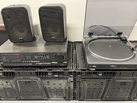 Photo shows an A.M. FM stereo receiver, a record turntable with dust cover, and two compact black speakers.