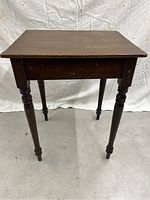 Front view of a small pine table with turned legs, showing the tabletop, apron, and four legs.