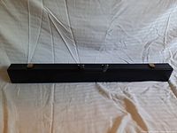 Black rectangular carrying case closed on wrinkled white cloth background.