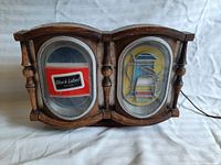 Front view of the lighted Black Label Beer sign showing wooden frame with two oval illuminated panels displaying the Black Label logo and beer pitcher graphic.
