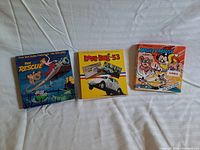 Three vintage Disney 8mm film boxes displayed side by side on a white fabric background.