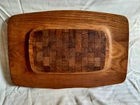 Overhead view of entire rectangular teak wood cheese tray with darker end-grain inset surface.