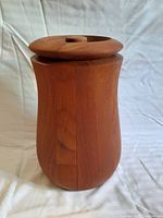 Front view of teak ice bucket with lid on, showing rounded shape and warm wood grain.