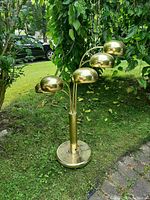 Full view of Mid Century Modern spider lamp with five brass dome shades outdoors on grass.