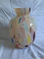 Front angled photo of a multicolor Murano style art glass vase showing its rounded body, flared mouth, and colorful swirls.