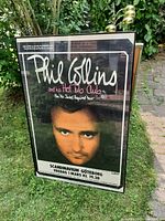 Framed poster showing Phil Collins with text about the concert and venue details.