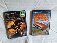 Photo showing two PlayStation 2 game cases: Shadow the Hedgehog with price tag and The Dukes of Hazzard Return of the General Lee.