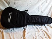 Black Archambault branded soft guitar case fully zipped closed, laid flat on white fabric background.