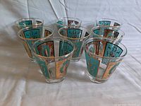 Set of 8 retro Mid-Century Modern glasses arranged in two rows, showing consistent and complete painted designs around each glass.