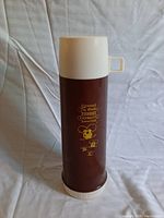 Full view of the brown and cream vintage Tim Hortons thermos with the logo and mouse design visible.