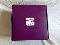 Closed purple box with white Silk'n logo on the top.