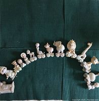 Top view of the 14 Precious Moments figurines arranged in a semi-circle on train cars on a green textile background.