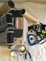 Photo showing beige and grey Petmate pet carrier, four cylindrical rope-covered scratching posts, assorted leashes and harnesses including blue bungee leash and bright yellow harness.