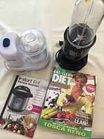 TopChop food chopper, Magic Bullet blender, and two recipe books displayed on white surface photographed from above.