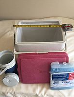 Overall view of all items: Coleman cold chest, Igloo thermos, red Coleman lid, Ice Pak cold pack with measuring tape for size reference.