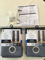 Two packaged grey Mainstay blackout grommet curtain panels, each 40 x 84 inches, with packaging labels visible.