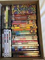 Photo of a large box filled with assorted DVDs, showing first layers of TV series and movie titles including Frasier and The Big Bang Theory.