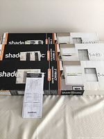 Three unopened boxes of Shade-O-Matic 2 inch privacy faux wood blinds with packaging showing brand and instructions.