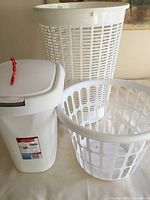 Rubbermaid 8 gallon garbage pail with hinged lid and two white round laundry baskets side by side