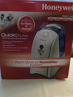 Front view of the humidifier box showing Honeywell branding, QuickSteam feature, and product details including warm moisture humidifier with visible moisture up to 3X faster, no filters to replace, and safety auto shut-off.