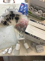 Wide photo showing many pieces including track light with two heads, various bulbs, white extension cord, white outlet plate, chain pulls, and packaging box for 9 pendant chandelier.