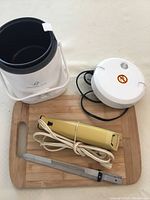 Photo of Wolfgang Puck mini rice cooker, electric carving tool with power cord and serrated blade, and bamboo cutting board.